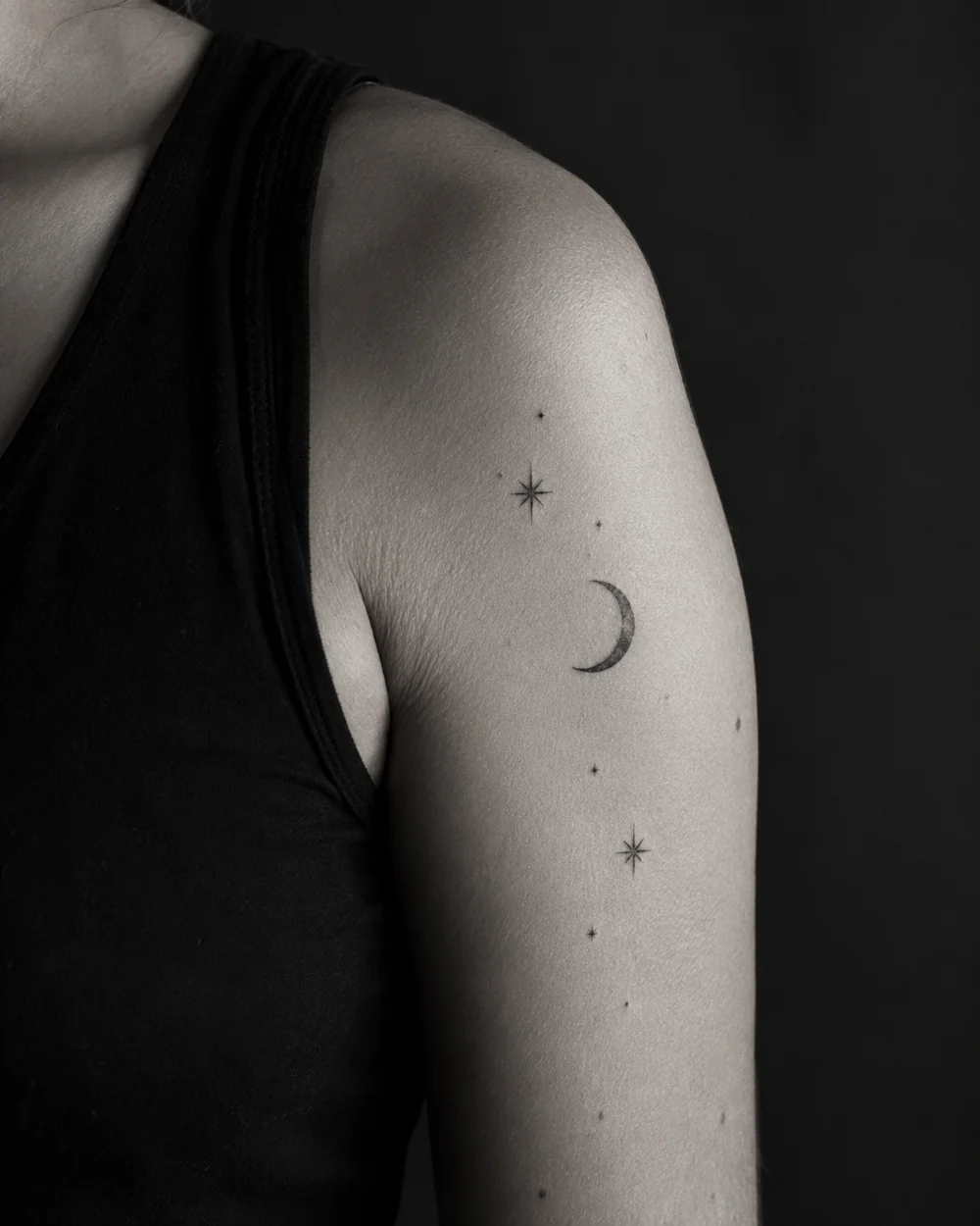 Celestial fine-line tattoo concept on an adult upper arm.